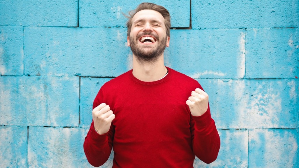 man wearing red long-sleeved shirt standing beside wall
