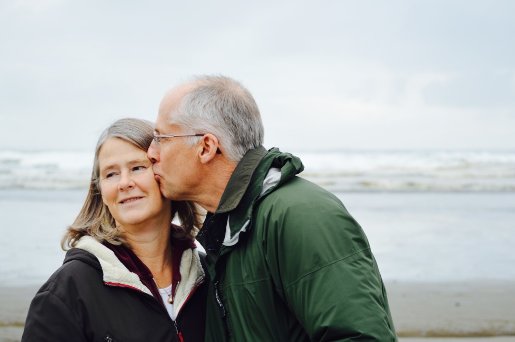 man kissing woman on check beside body of water